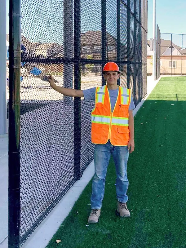 Ariel Sima setting a fence post on a job site