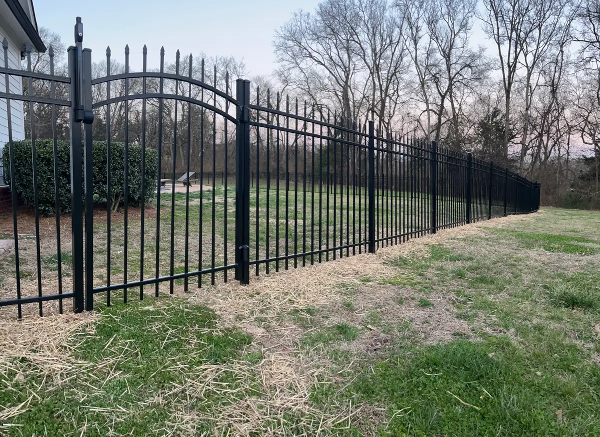 Black aluminum fence running the length of a rural property line