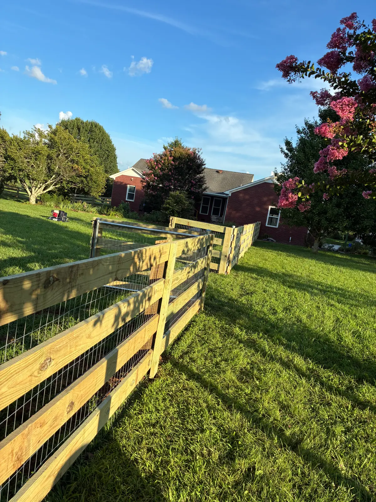 Yellow wood ranch fence with mesh gates, installed by Duck Duck Fence