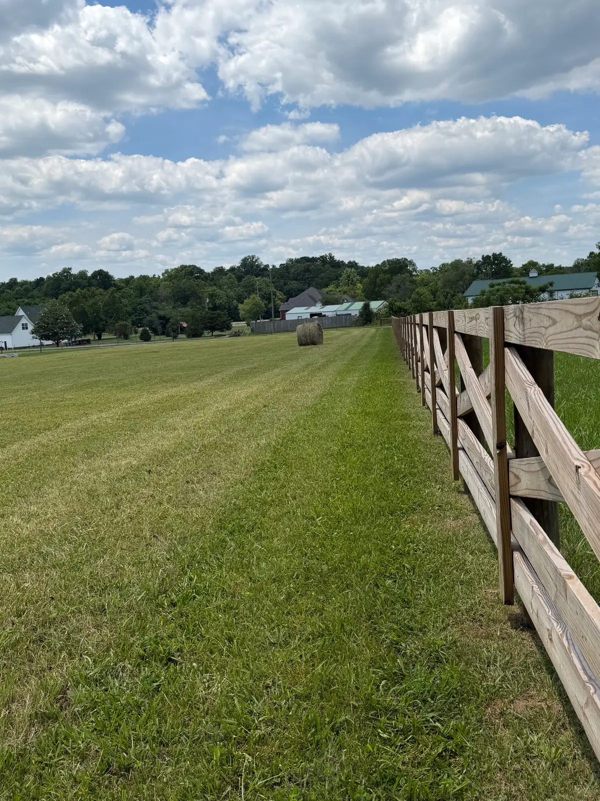 Wood board ranch fence running along rolling farmland