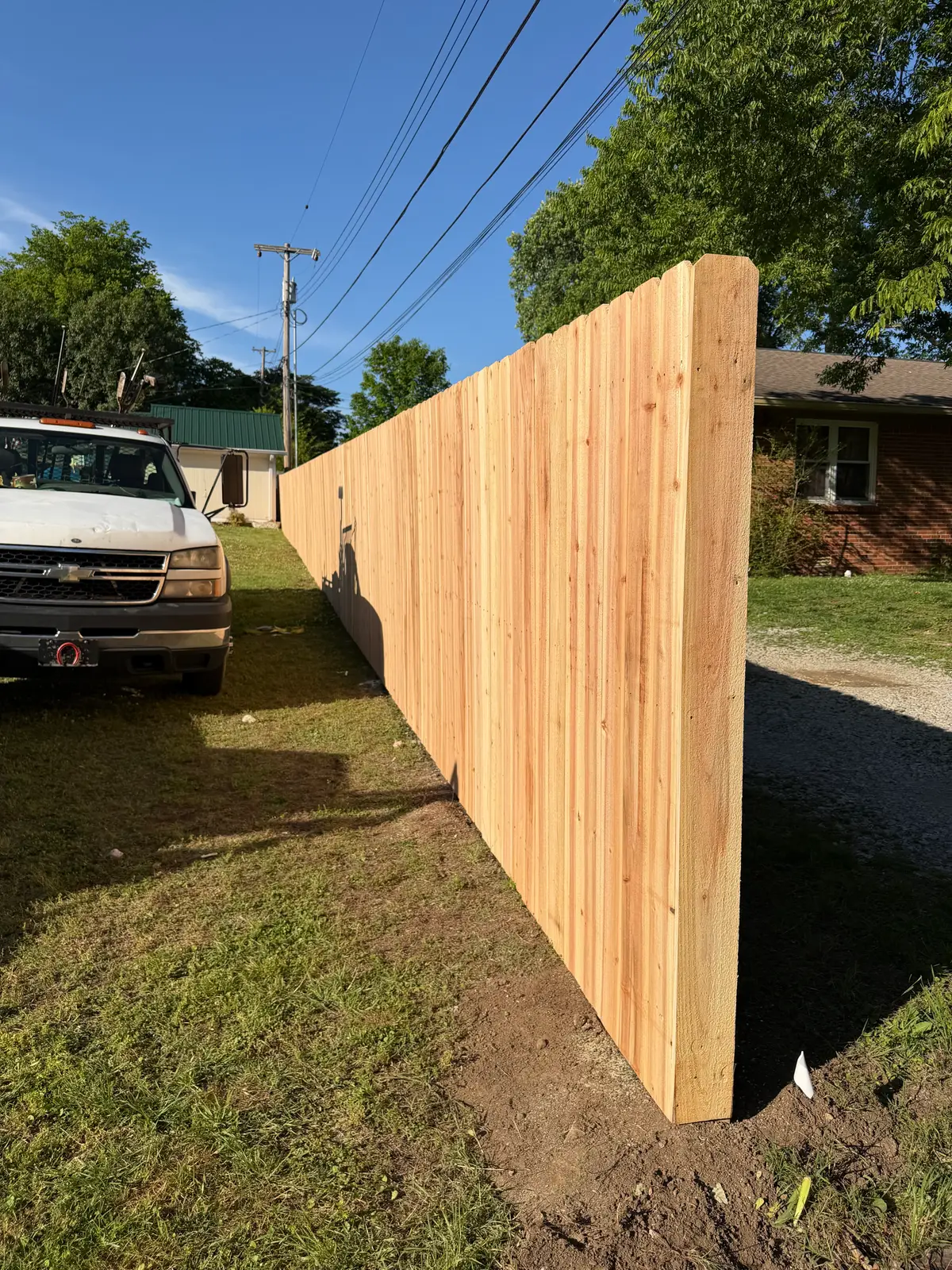 Cedar board privacy fence beside a gravel driveway