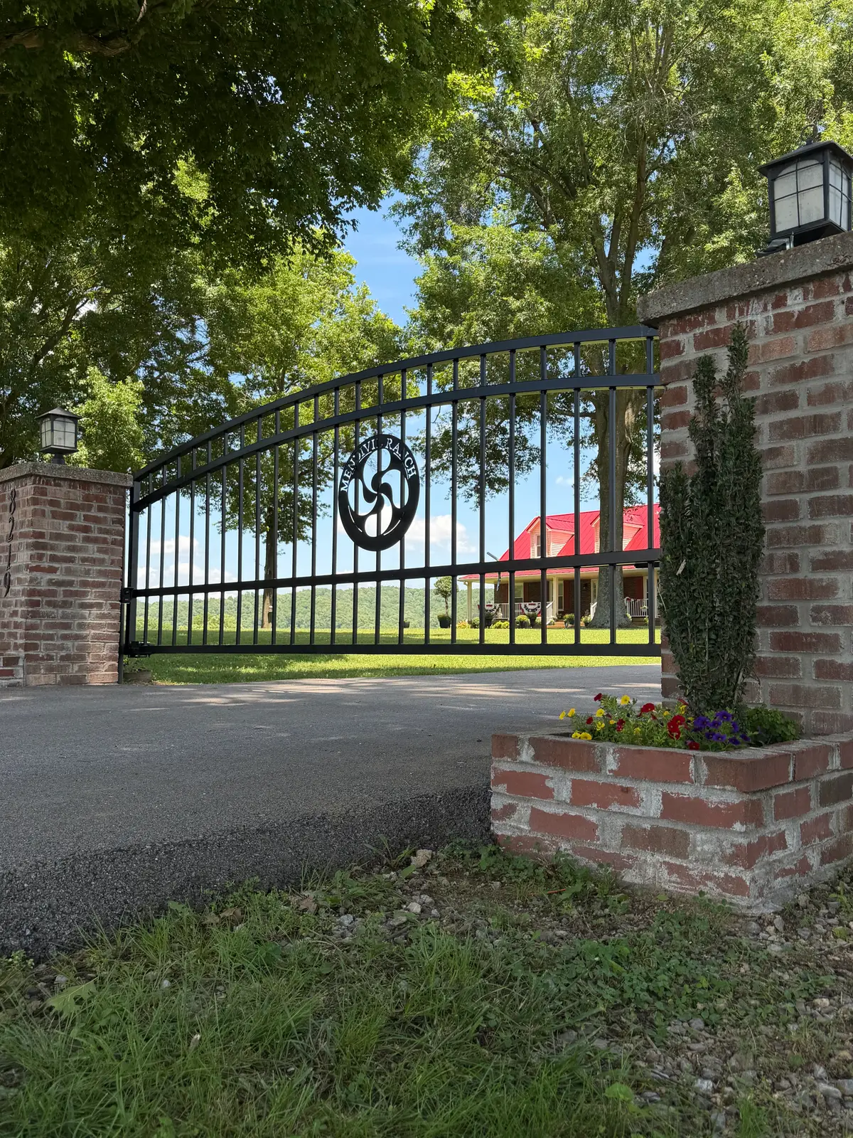 Arched black metal driveway gate between brick columns