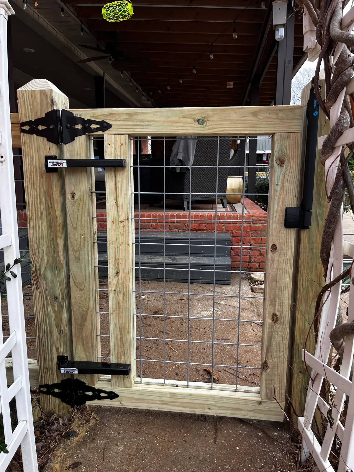 Wood-frame wire farm gate set into a board fence