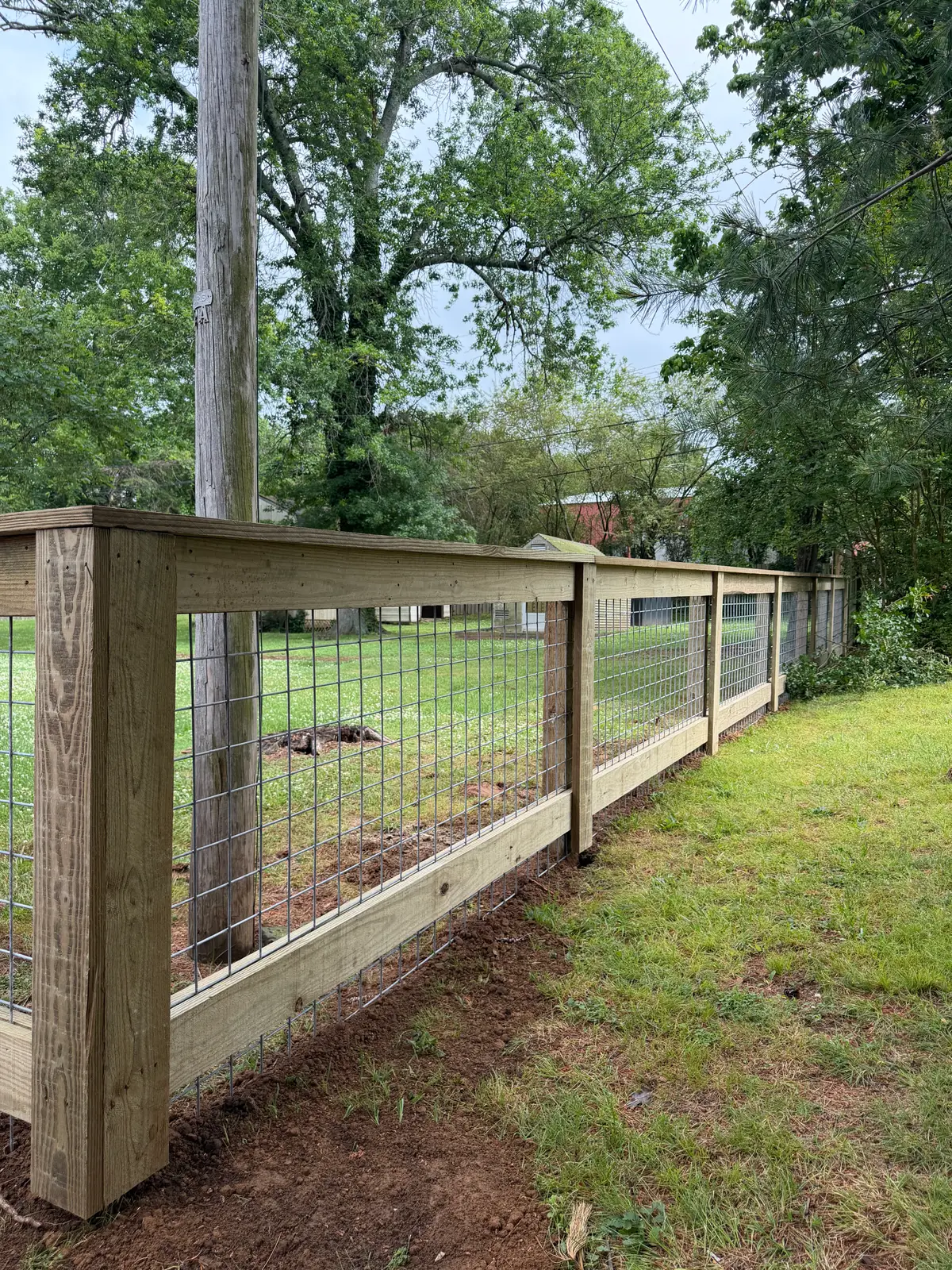 Woven-wire fence on wood posts around a horse enclosure
