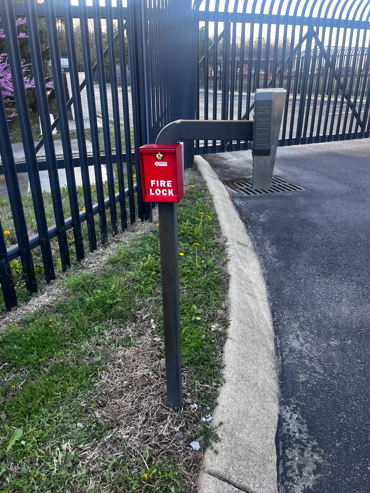 Black aluminum fence beside a paved walkway with a Fire Lock box
